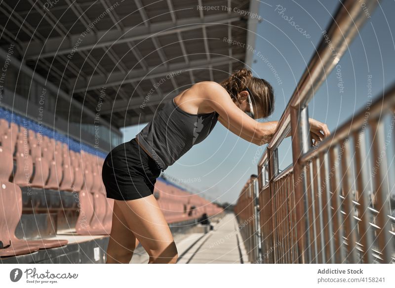 Athletic woman resting after workout at stadium sportswoman tired training fit fitness exercise recreation exhausted relax break sporty active slim female