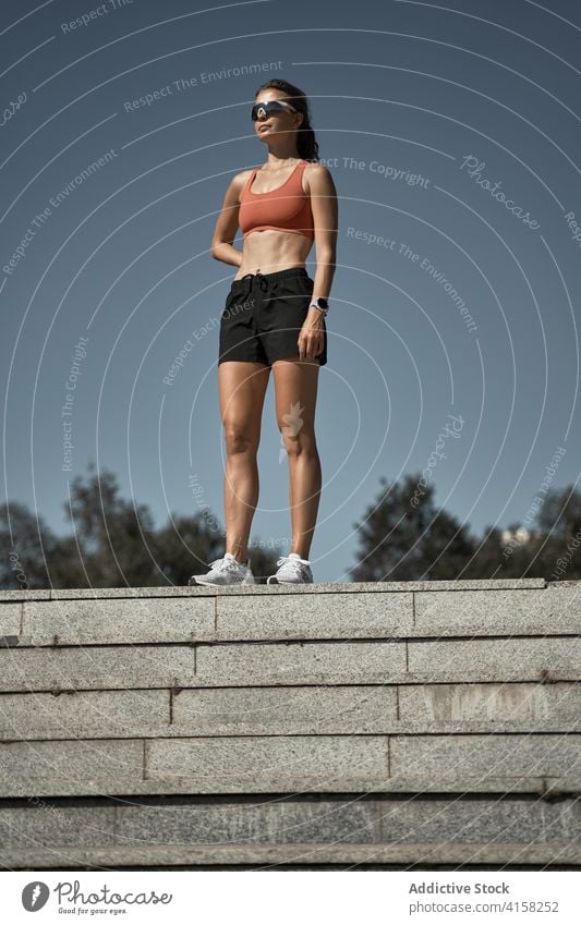 Young fit woman in sportswear standing on stairway on street sportswoman slim step confident training workout fitness recreation exercise relax break sporty