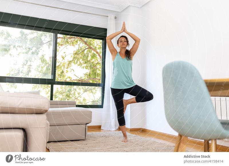 Relaxed woman doing yoga in Tree pose at home tree pose meditate vrksasana harmony practice balance barefoot female vitality tranquil serene slim peaceful