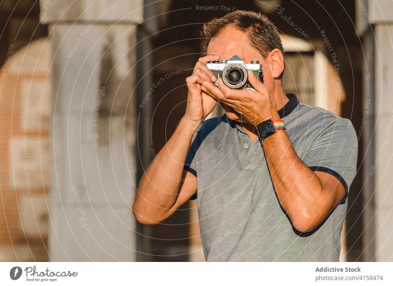 Man taking picture on vintage camera in city photographer retro street man photo camera take photo sunny summer male hobby memory photography professional
