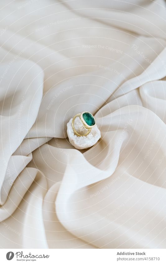 Elegant ring placed on white quartz elegant precious gem jewelry luxury stone natural accessory piece soft bed silk fabric textile cloth delicate bedroom
