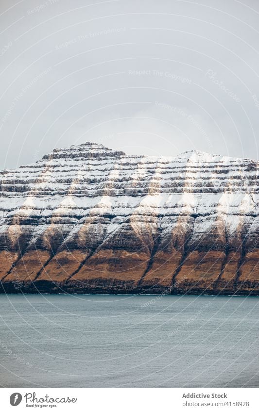 Rocky cliff near sea on Faroe Islands rock seascape winter snow season cold steep terrain faroe islands rocky scenery majestic coast shore water sky calm