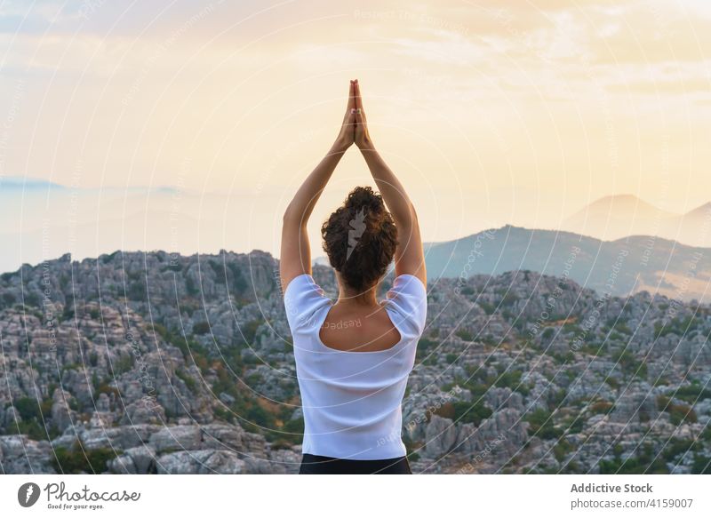 Concentrated woman practicing yoga in mountains at sunset star reverse prayer hands rock nature practice asana pose position wellness harmony balance wellbeing