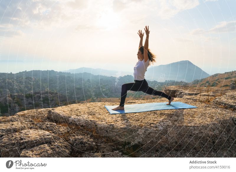 Concentrated woman practicing yoga in mountains at sunset rock nature practice asana pose position wellness harmony balance wellbeing zen health care