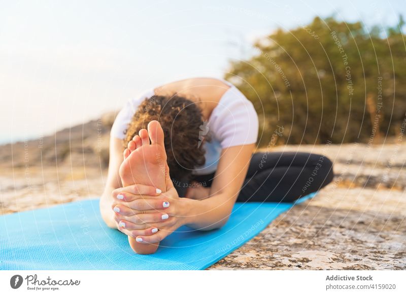 Flexible woman stretching in yoga asana in nature head to knee sit forward bend janu sirsasana flexible pose mountain rock practice position wellness lifestyle