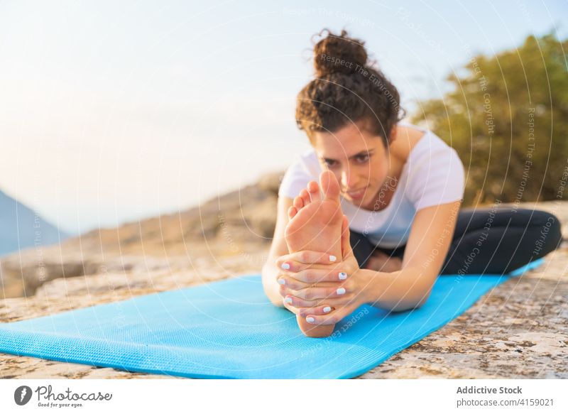 Flexible woman stretching in yoga asana in nature head to knee sit forward bend janu sirsasana flexible pose mountain rock practice position wellness lifestyle