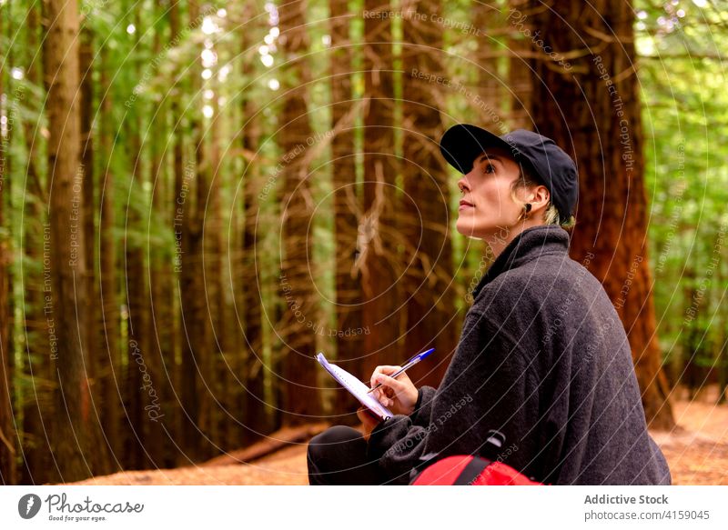 Traveling woman taking notes in notebook in woods explorer take note forest journey destination tourist tree female cantabria