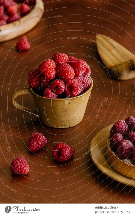 Cup full of delicious ripe raspberries on table cup raspberry vitamin sweet tartlet dessert fresh wooden red tasty fragrant treat heap yummy baked decoration