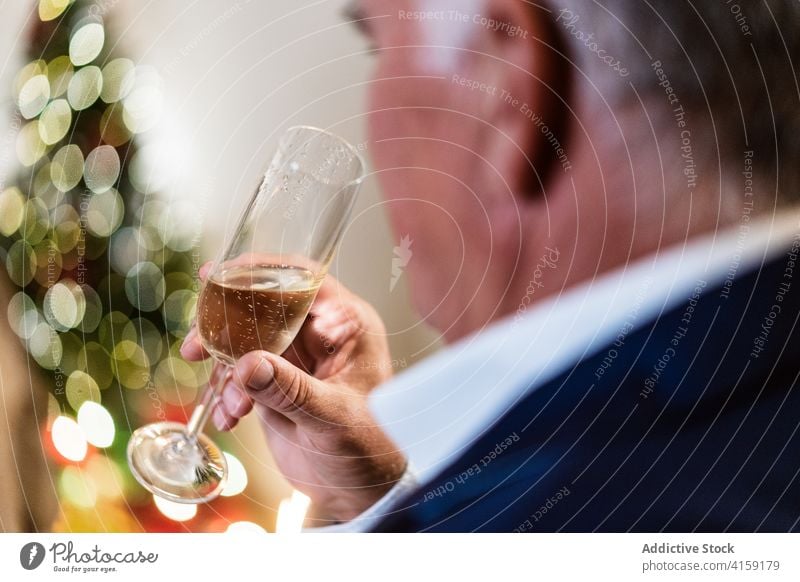 Elegant man drinking champagne at Christmas at home christmas table elegant holiday mature celebrate festive male serious party merry alcohol glass outfit