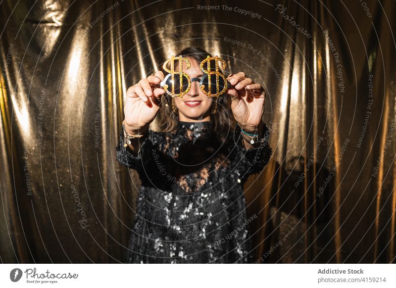 Carefree woman in party glasses and dress sunglasses glamour golden celebrate having fun holiday dark shimmer female fancy black content trendy fashion happy