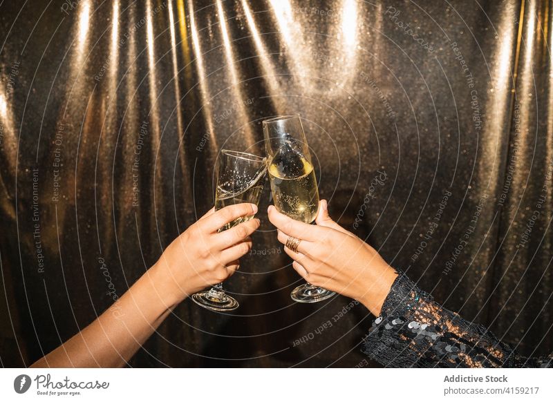 Crop women clinking glasses at party champagne celebrate toast golden alcohol holiday shiny friend drink festive event occasion sparkle beverage together cheers