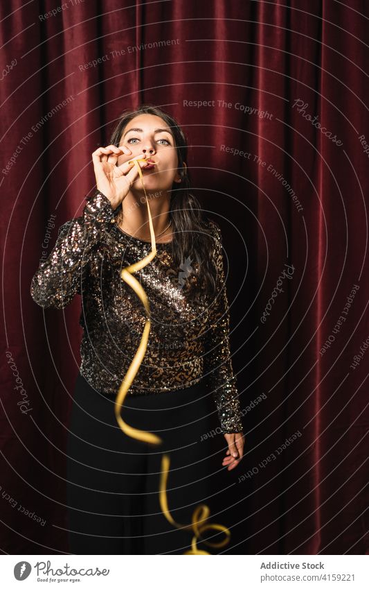 Stylish woman blowing party whistle horn glamour celebrate glitter entertain having fun female dress bright vivid vibrant holiday event young style trendy