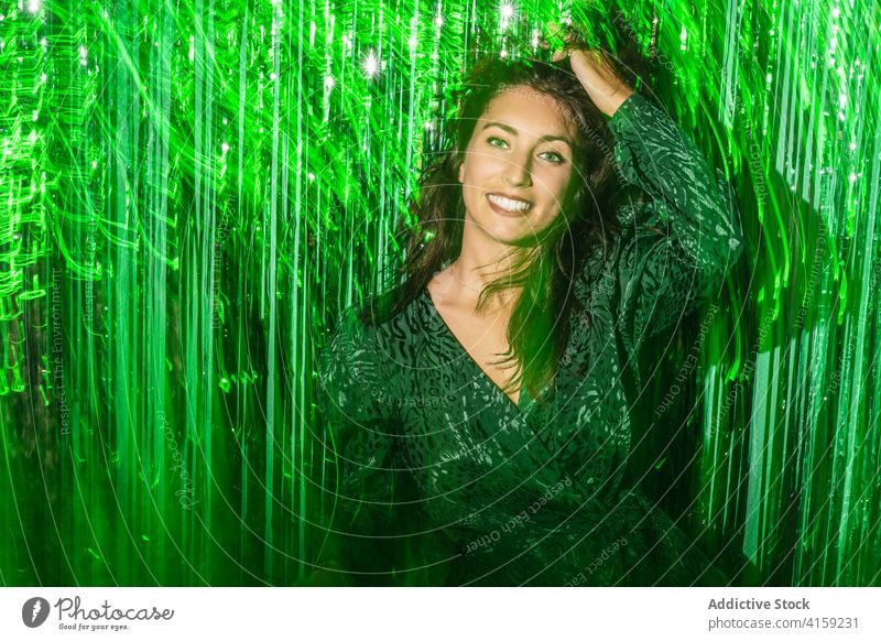 Cheerful woman playing with green tinsel party stripe having fun playful foil color vibrant female shiny dress festive happy cheerful delight enjoy trendy