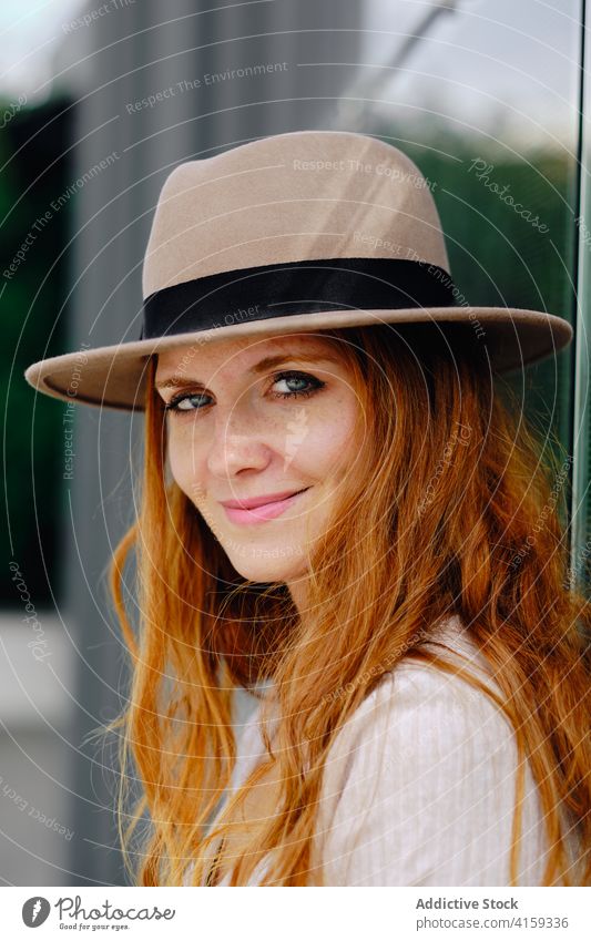 Charming red haired woman in hat standing on street redhead style smile trendy urban modern positive young female fashion long hair lady confident charming
