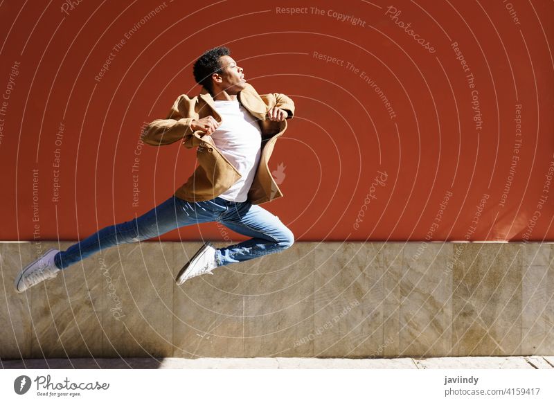 Young black man doing an acrobatic jump in the middle of the street. jumping happiness male cuban young person happy dancer outdoor one acrobatics joy casual