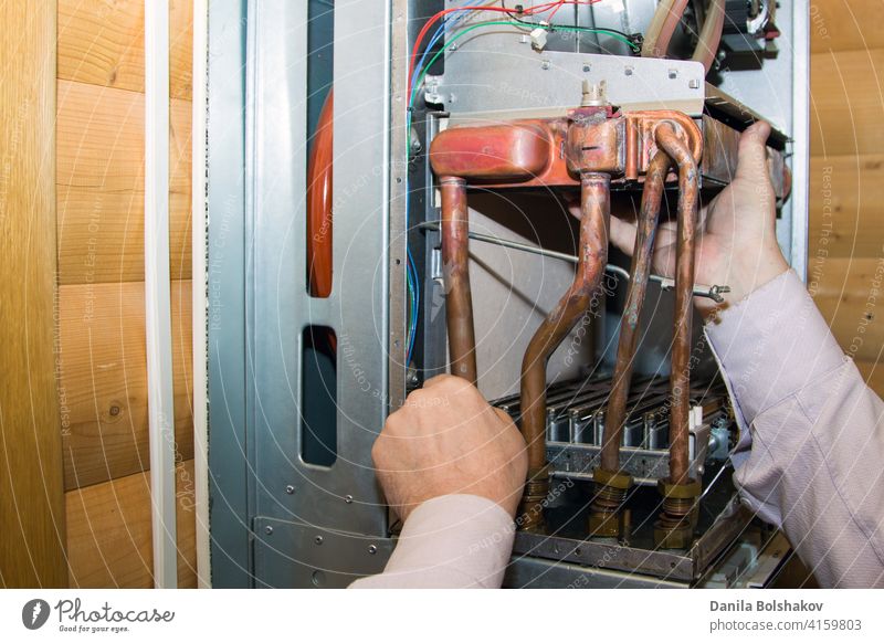 worker installs the heat exchanger after descaling on a workplace in the gas boiler adjustable adult appliance basement business caucasian construction energy