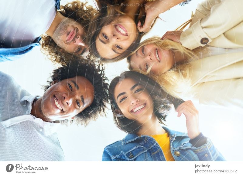 Multi-ethnic group of friends with their heads together in a circle. people young multi-ethnic multiracial diversity lifestyle outdoors portrait women laughing