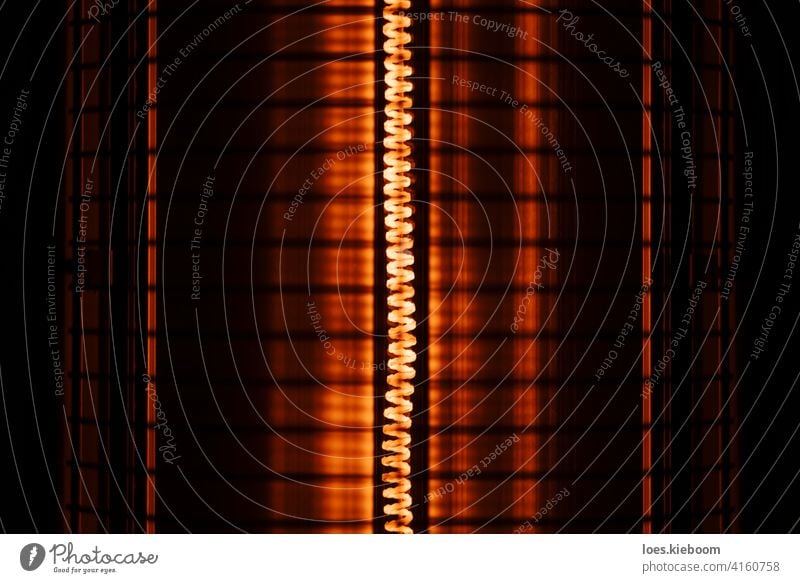 Close up of an electric heater coil with grill protection warm hot light red mesh winter temperature background design abstract pattern texture electricity