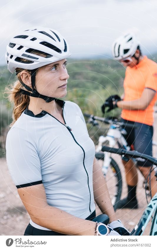 Serious female cyclist standing with bicycle in countryside bicyclist helmet woman sport rider protect together nature confident bike transport vehicle extreme