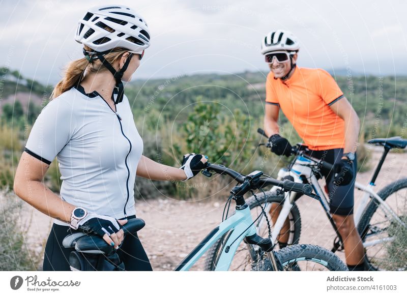Couple of cyclists with bicycles in nature bicyclist couple rider cheerful together transport fit sunglasses helmet protect glove extreme modern young stand mtb