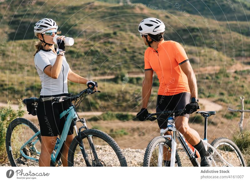 Bicyclists relaxing during ride in mountains bicycle couple together sport break training drink water highland area rest healthy sporty athlete wellbeing