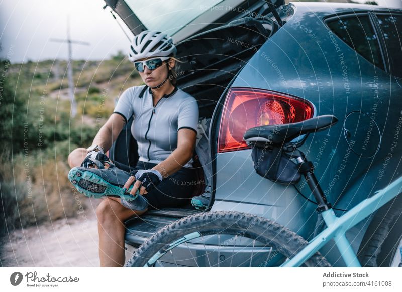Determined female cyclist preparing for ride bicyclist helmet trunk car woman prepare bicycle rider professional determine sunglasses sit confident modern