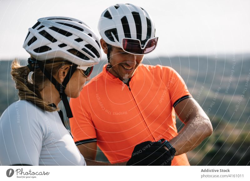 Couple of cyclists checking time on wristwatch bicyclist together couple bracelet smart watch time management accuracy gadget device hill punctual sporty