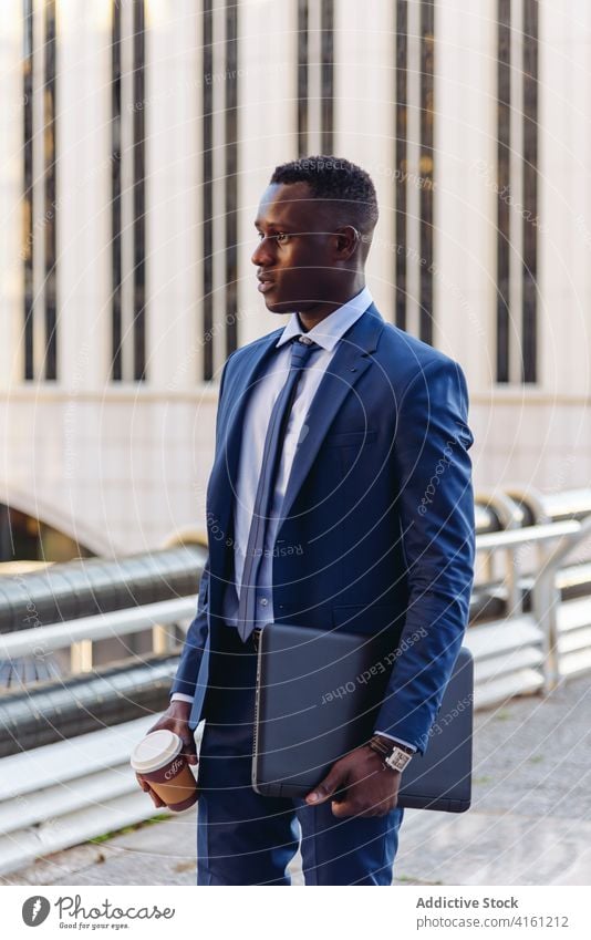 Stylish executive black man in suit walking in downtown - a