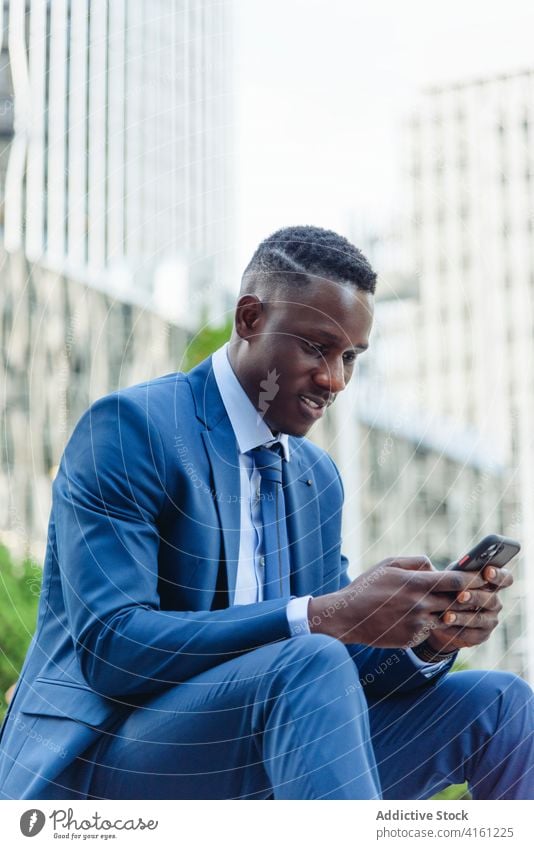 Cheerful ethnic businessman using phone on street confident talk happy success cheerful formal urban suit modern elegant executive manager professional adult