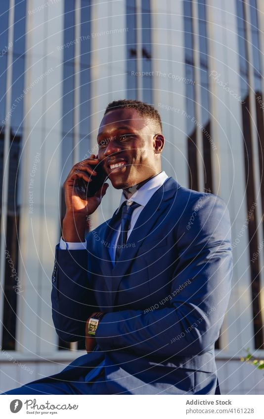 Cheerful ethnic businessman talking on phone on street confident happy success cheerful formal urban suit modern elegant executive manager professional adult