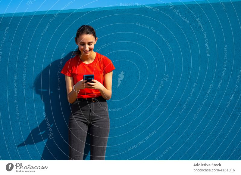 Woman dressed in red using the mobile on a blue background. Concept of using the mobile. Blue background. using mobile woman technology using cell phone