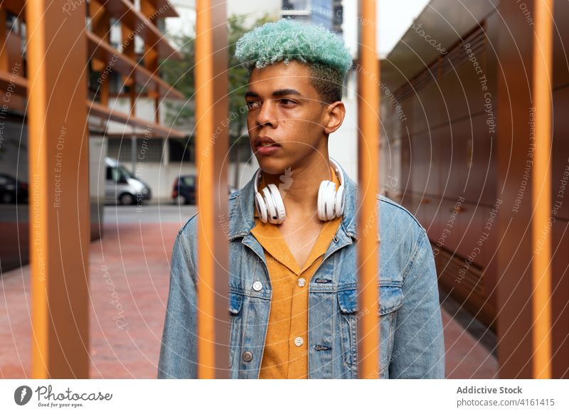 Pensive ethnic man with blue hair in city hipster street style generation young dyed hair appearance handsome male black african american urban fence modern