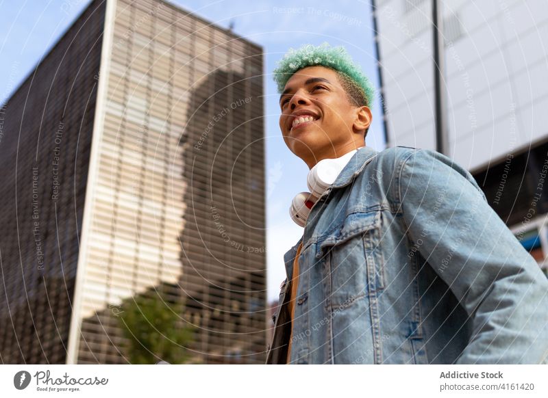 Delighted trendy black man in city hipster blue hair dyed hair street cheerful appearance hairstyle male ethnic african american cool fashion modern confident