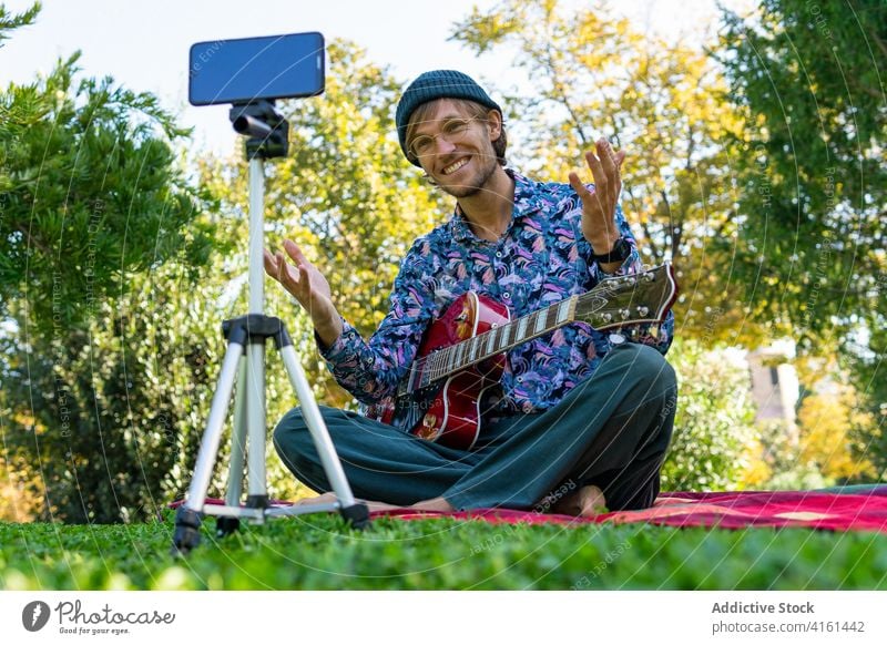 Male guitarist recording video in park blogger man musician smartphone male electric modern sound internet social media song mobile instrument guy gadget sit