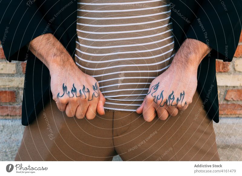 Faceless man showing ornamental tattoo on hands style creative design modern street town stylish apparel brick wall appearance trendy shabby rough natural
