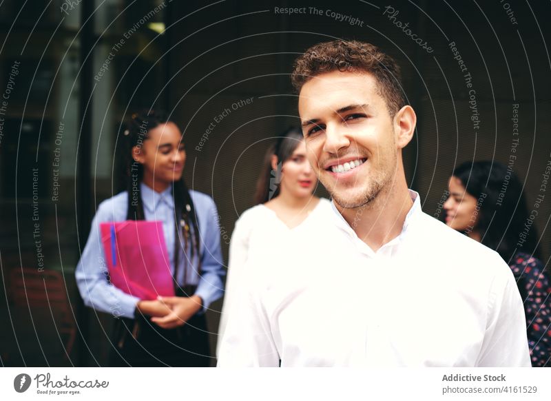 Positive student in front of multiethnic colleagues on street smile sincere braid folder pleasant friendly coworker talk man stylish apparel partner
