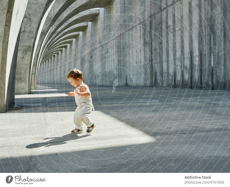 Cheerful toddler walking under arched construction cheerful kid child city cute delight smile curious pathway adorable architecture walkway carefree positive