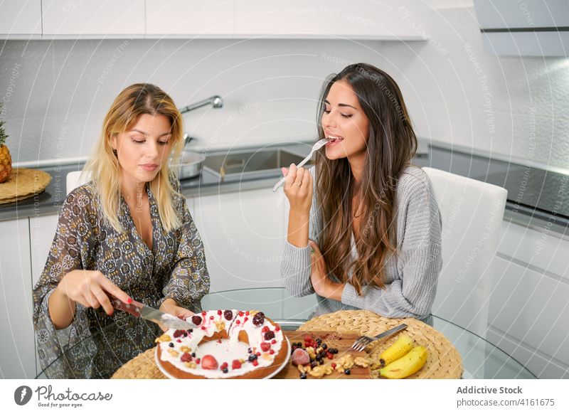 Happy women eating vegan dessert in kitchen healthy food cake enjoy pastry homemade diet berry young female sweet delectable tasty delicious girlfriend positive