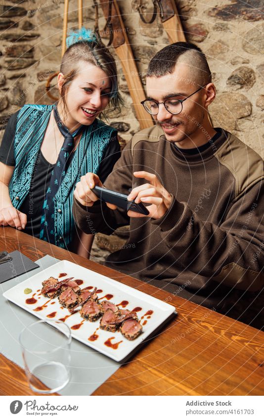 Delighted friends taking photo of delicious dish take photo food food photography blogger hipster together cafe relax smartphone entertain palatable meat plate