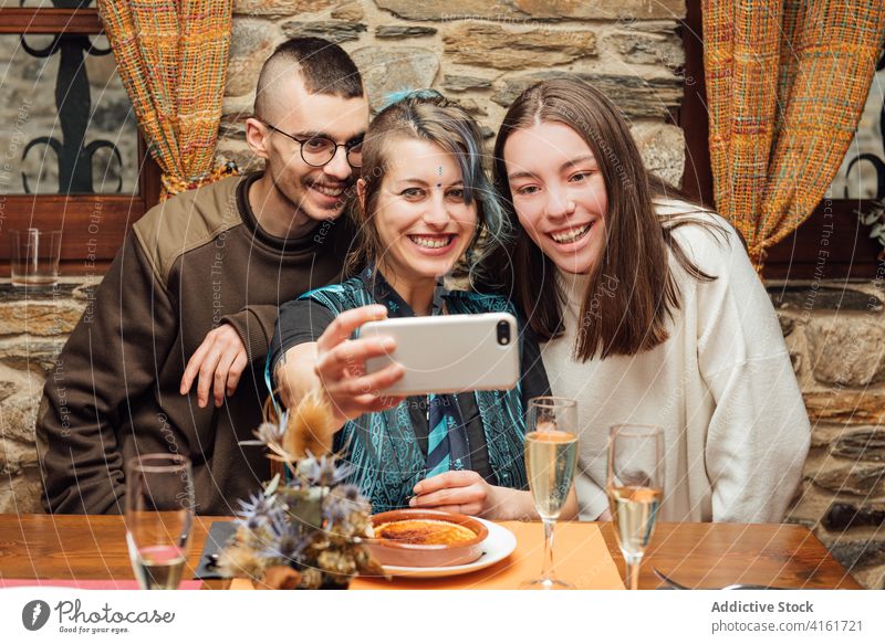 Cheerful friends taking selfie in cafe hipster company smartphone gather friendship self portrait having fun fancy appearance table smile happy cheerful memory