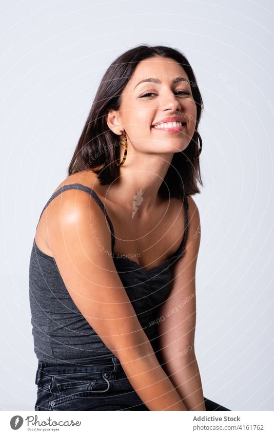 Cheerful woman sitting on stool in studio toothy smile joy excited cool appearance expressive gorgeous carefree cheerful attractive young slim chair trendy