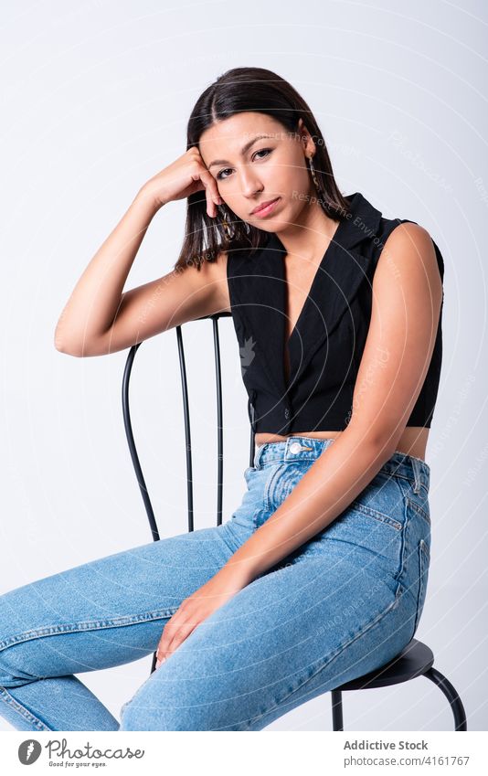 Woman sitting on chair in studio woman cool appearance attractive young slim trendy sensual vogue flexible female energy feminine individuality style skinny