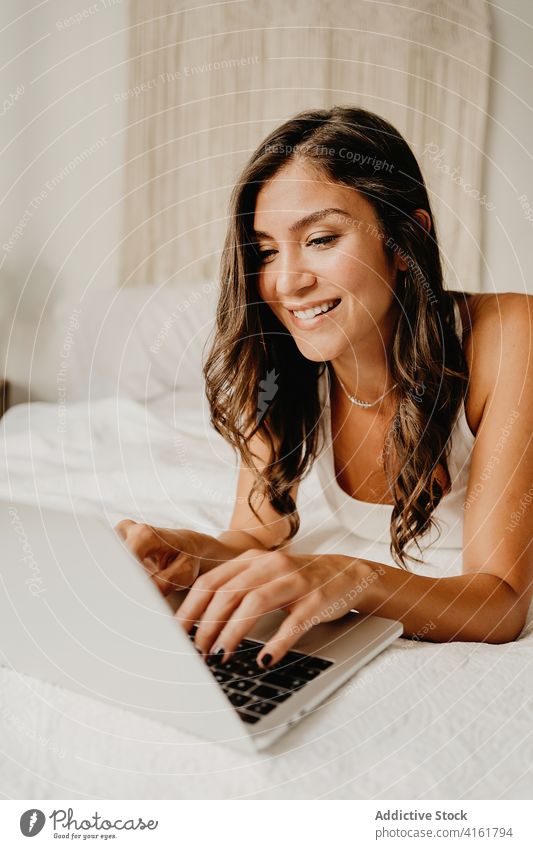 Joyful woman browsing laptop on bed morning using happy bedroom home cheerful young female device gadget internet cozy carefree chill student online delight