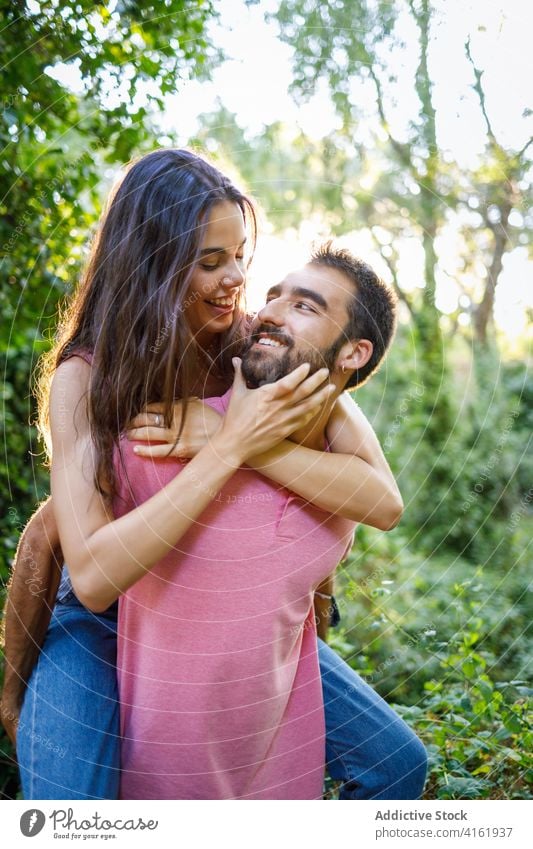 Playful young ethnic couple having fun in park happy love relationship playful piggyback romantic touch face smile affection together spend time date girlfriend
