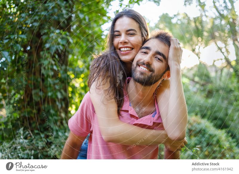 Playful young ethnic couple having fun in park happy love relationship playful piggyback romantic touch face smile affection together spend time date girlfriend