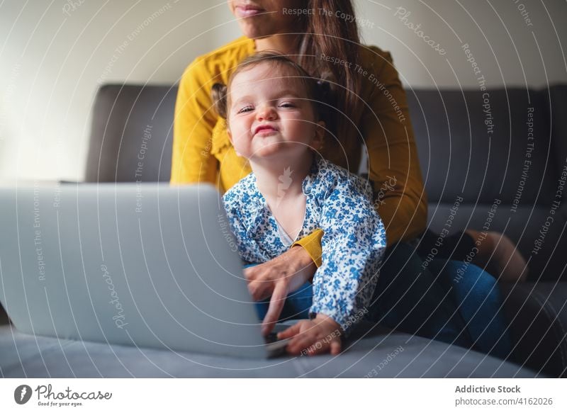 Woman with little kid using laptop at home mother work busy toddler remote daughter child together motherhood gadget device lifestyle mom browsing freelance