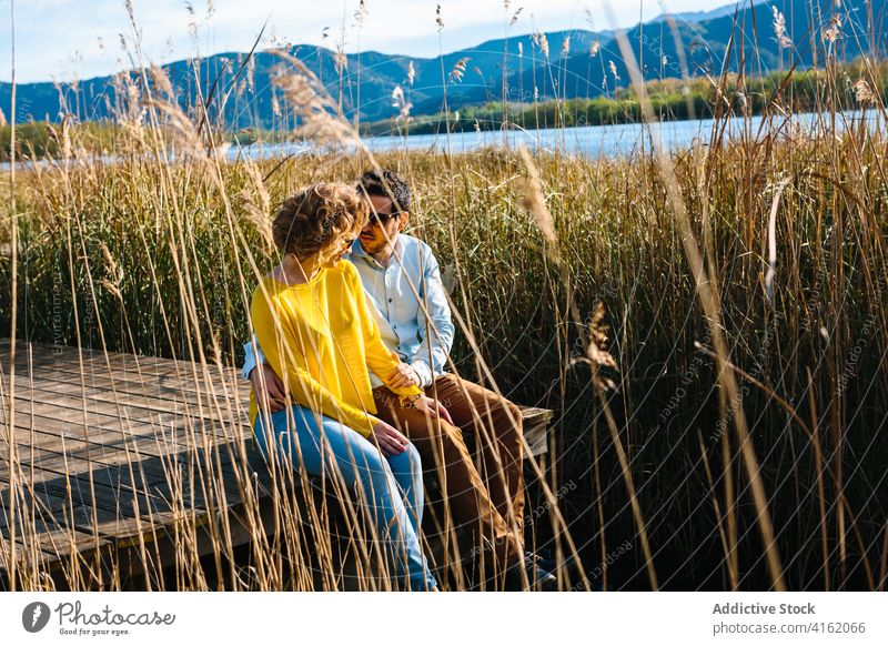 Couple sitting on wooden quay in summer couple pier lake mountain relationship relax together hug sunlight love carefree freedom romantic embrace sunny