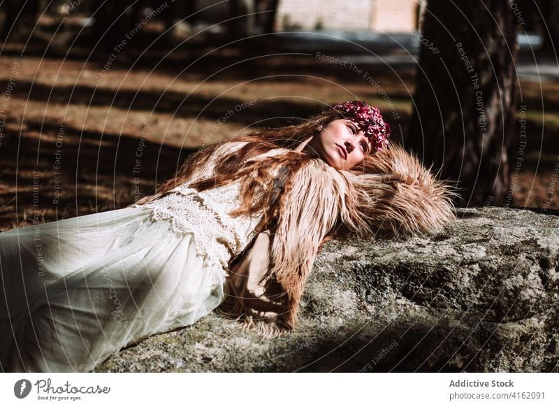 Sensual woman in traditional Nordic outfit lying on stone nordic fashion style sensual dreamy wedding fur scandinavian charming bridal young female model dress