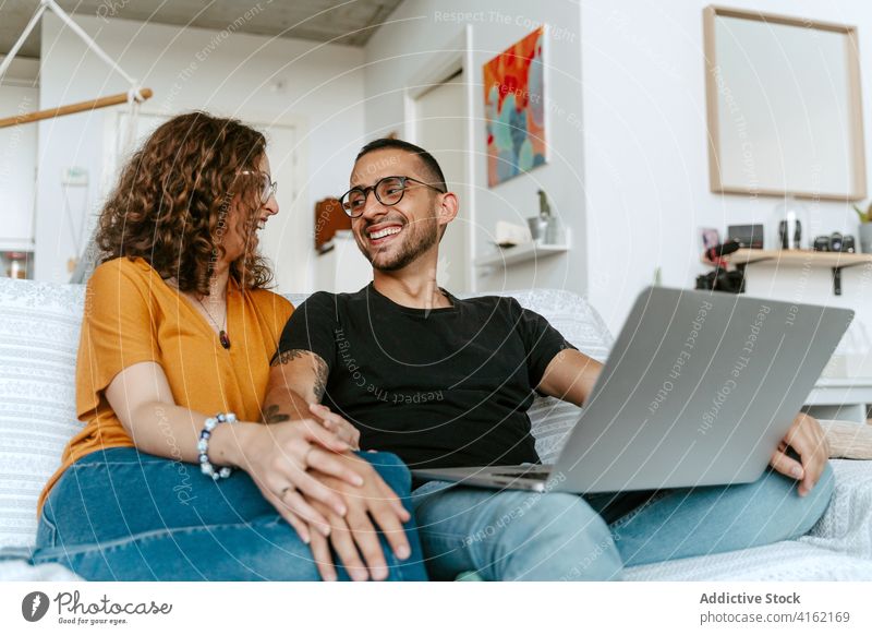 Happy couple having video conversation on laptop at home video call happy together holding hands sofa wave hand cheerful connection relationship boyfriend