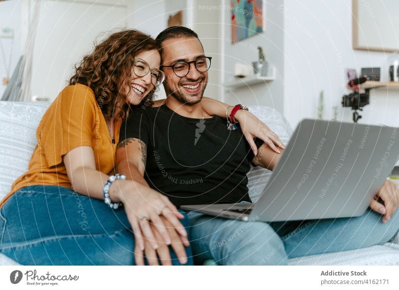 Happy couple having video conversation on laptop at home video call happy together holding hands sofa wave hand cheerful connection relationship boyfriend